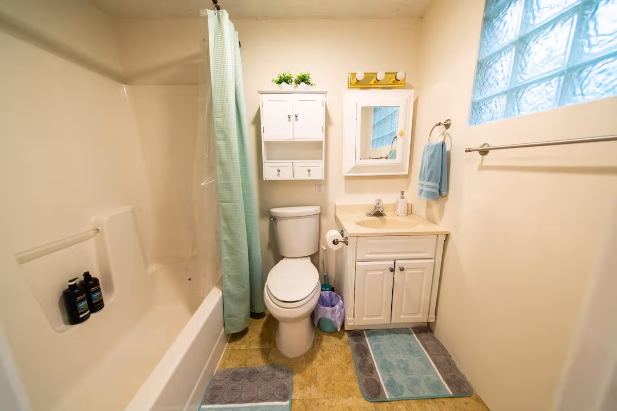 Buck Cottage bathroom with tub-shower, toilet, and vanity