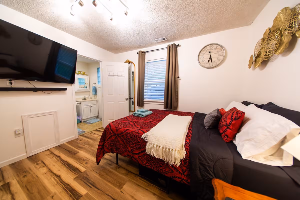 Buck Cottage bedroom with bed, wall-mounted TV, and ensuite doorway