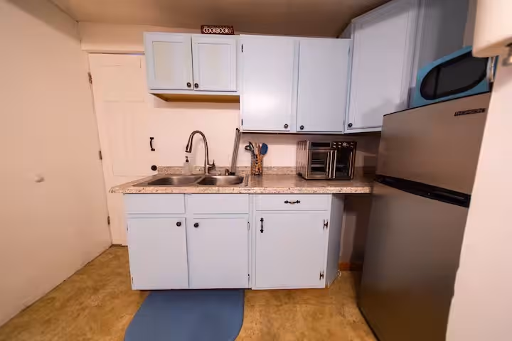 Buck Cottage kitchen with pale blue cabinets, double sink, and refrigerator