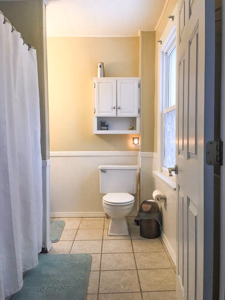 Frederick Cottage bathroom with shower, toilet, wall cabinet, and tile floor