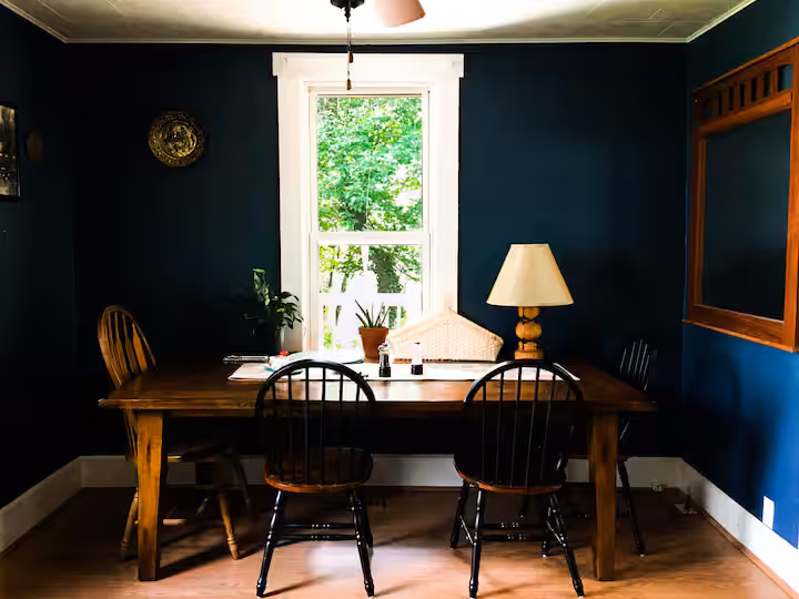 Frederick Cottage dining nook with wooden table, spindle chairs, window, and lamp