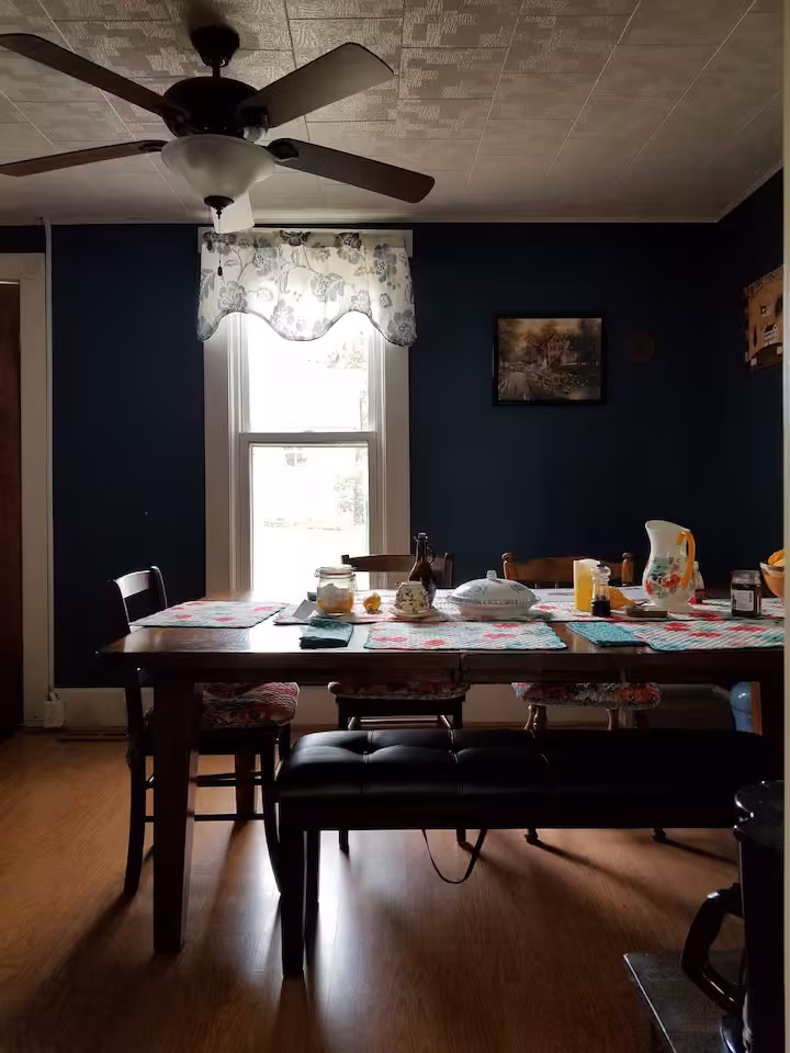 Frederick Cottage dining room with set table, bench seating, ceiling fan, and window