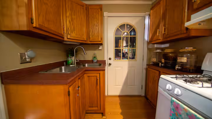 Frederick Cottage kitchen sink with oak cabinets, glass-paneled door, and gas range