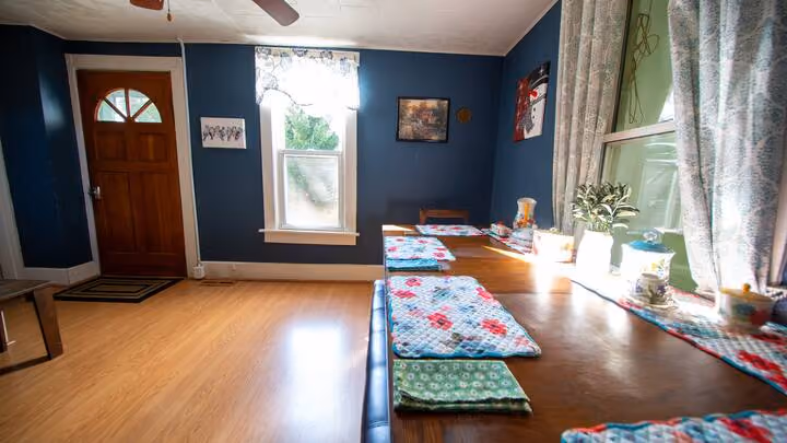 Frederick Cottage main room with long wooden table, blue walls, door, and windows
