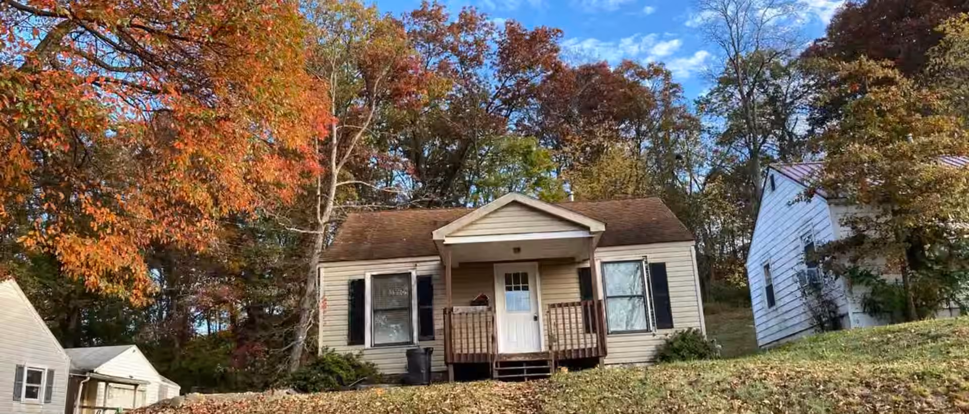 Buck Cottage front exterior with porch, centered entry, and mature trees