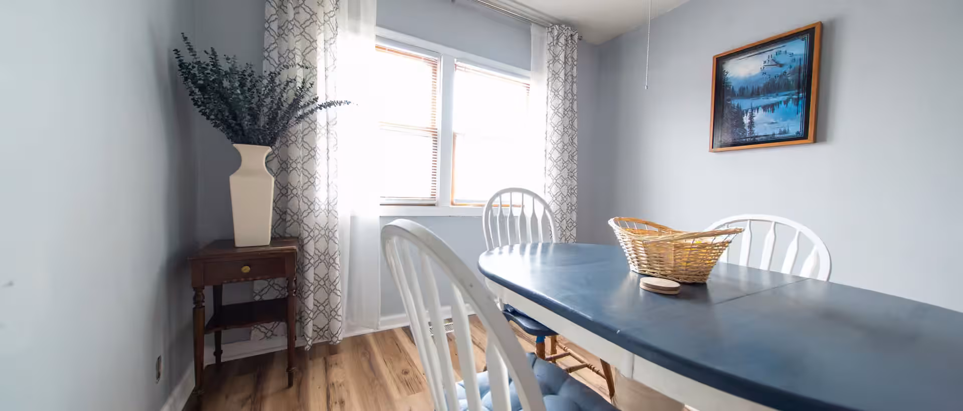 Oak Cottage bright dining room with blue table, white chairs, and window