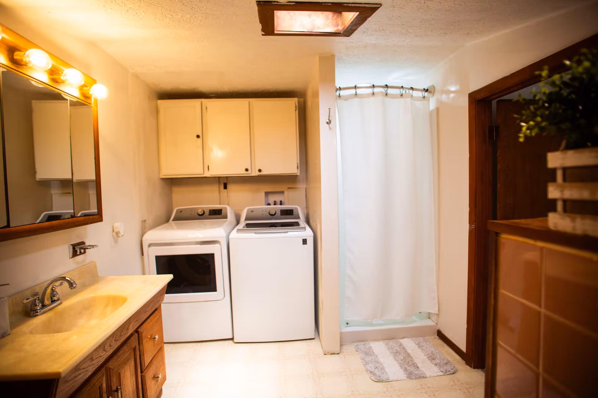 Broad Cottage bathroom shower area with sink, mirror, and cabinets