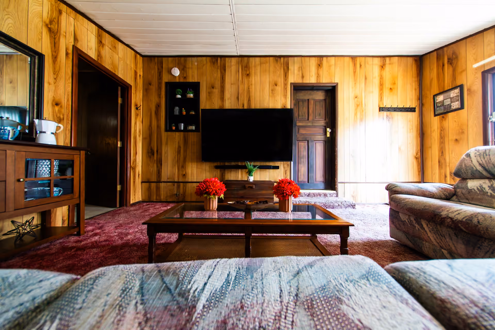 Broad Cottage wood-paneled living room with sectional seating and television