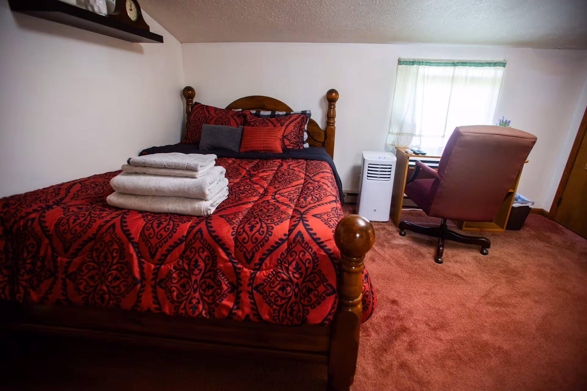 Broad Cottage bedroom with a queen bed, nightstand, hardwood floor, large window, and visible desk chair